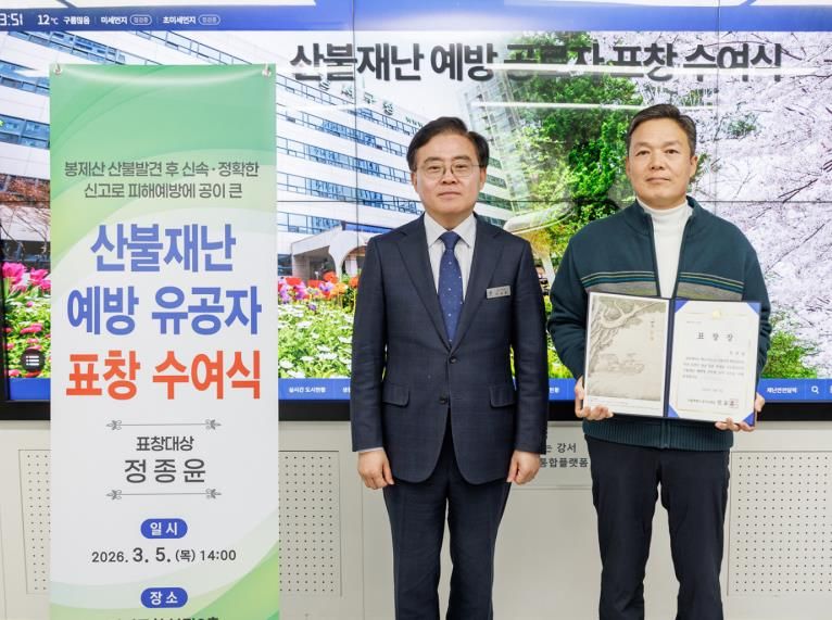 진교훈 서울 강서구청장(왼쪽)이 지난 5일 구청에서 열린 ‘산불재난 예방 유공자 표창 수여식’에서 신속한 신고로 초기 진화에 기여한 화곡동 주민 정종윤(57) 씨에게 표창을 수여하고 기념촬영을 하고 있다.